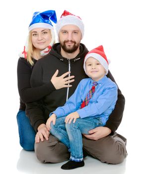 Happy family of 3 people in caps of Santa Claus, the Christmas tree and the fireplace in the Christmas night.Isolated on white background.