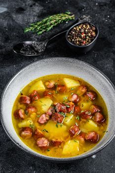 German Split pea soup with smoked sausages and meat. Black background. Top view.