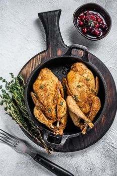 Whole roast quails in a pan. White background. Top view.