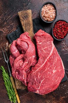 Raw Beef meat fillet Sliced on wooden cutting board. Dark background. Top view.