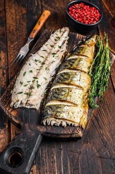 Roasted fillets of mackerel fish on cutting board. Dark wooden background. Top view.
