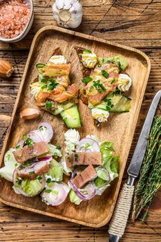 Open sandwich with salmon and herring, cream cheese and salad on a cutting board. wooden background. Top view.