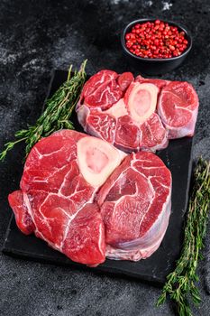 Raw beef meat osso buco shank steak, italian ossobuco. Black background. Top view.