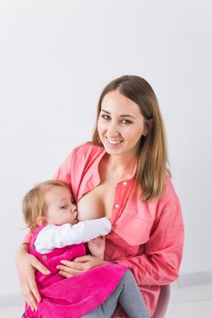 Lactation and motherhood concept - Young beautiful mother holding breastfeeding baby sitting on chair