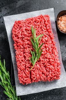 Fresh Raw mince beef, ground meat on butcher paper. Black background. Top view.