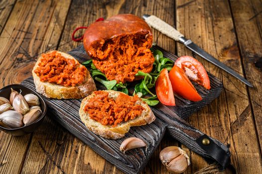 Tapaa sandwichs with Sobrassada cured pork meat sausage and tomato on a wooden cutting board. wooden background. Top view.