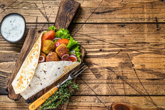 Vegetarian Tortilla wrap with falafel and fresh salad, vegan tacos. wooden background. Top view. Copy space.