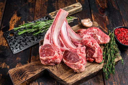 Lamb raw chops steaks on butcher cutting board. Dark wooden background. Top view.