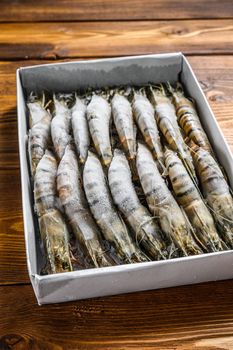 Package of frozen tiger prawns, shrimps. Wooden background. Top view.