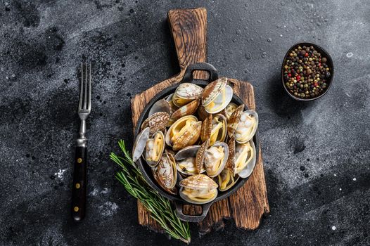 Cooked Clams vongole in a pan. Black background. Top view.