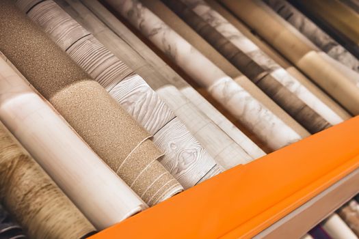 Assortment of light white wallpaper in rolls in a hardware store.