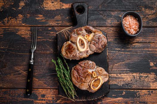 Stewed meat on the bone Osso Buco beef shank, italian ossobuco steak. Dark wooden background. Top view.