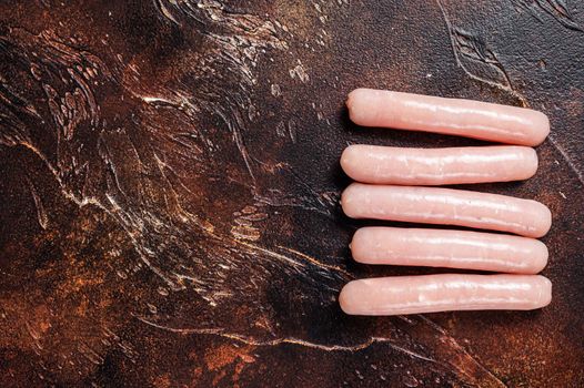 Raw chicken and turkey meat sausages on butcher table. Dark background. Top view. Copy space.