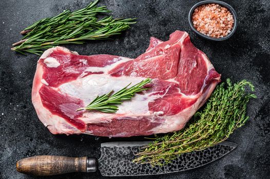 Fresh Raw lamb mutton shoulder meat with butcher knife. Black background. Top view.