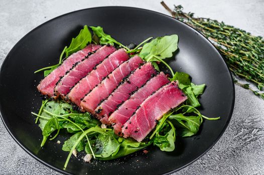 Tuna steak salad with arugula and spinach. White background. Top view.