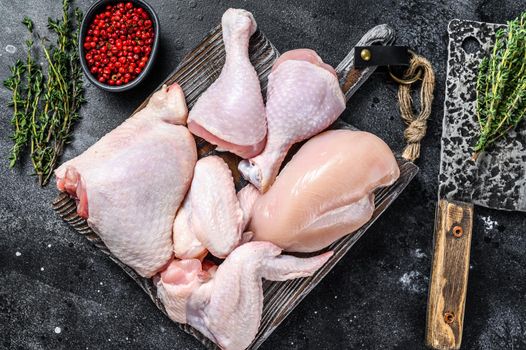 Fresh raw chicken meat, wings, breast, thigh and drumsticks. Black background. Top view.