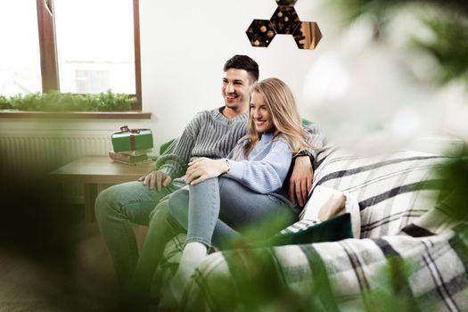 Sweet couple embracing on sofa at home during christmas holidays