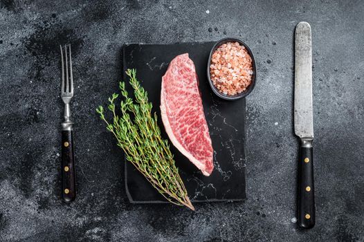 Wagyu raw sirloin steak, kobe beef meat on marble board. Black background. Top view.