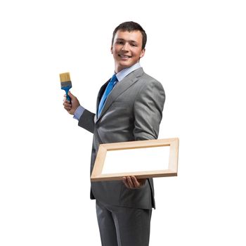 Creative businessman painter holding paint brush and whiteboard in hands. Portrait of happy handsome man in business suit and tie isolated on white background. Ambitions and creativity in business.