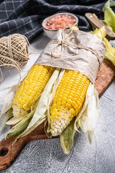 Fresh harvested corn cob on farmer market, local vegetables. Gray background. Top view.