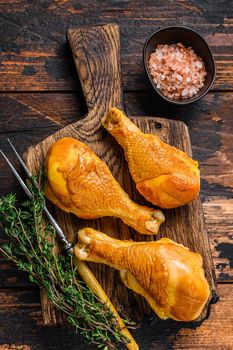 Marinated and Smoked chicken legs drumsticks on a wooden cutting board. Dark wooden background. Top view.