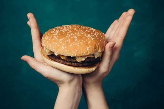 hamburger in hands close-up fast food green background. High quality photo