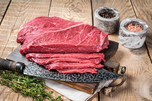 Sliced piece of marble raw beef meat on wooden cutting board. wooden background. Top view.