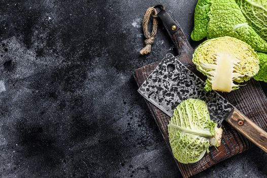 Cut Fresh healthy savoy cabbage on cutting board. Black background. Top view. Copy space.