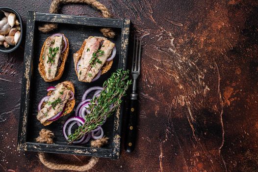 Tapas with sardine and sprat, cream cheese and onion. Dark background. Top view. Copy space.