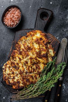 Potato pancakes with herbs and salt on wooden board. Black background. Top view.