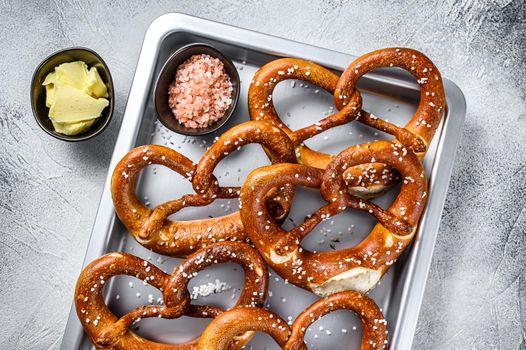 Salted pretzels with sea salt on a kitchen baking pan. White background. Top view.