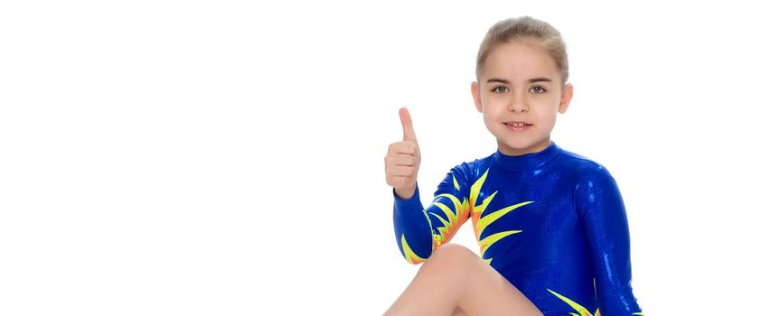 A charming gymnast girl, a younger school age, in a beautiful blue swimsuit, performs an exercise on the floor.She looks directly into the camera.Isolated on white background.
