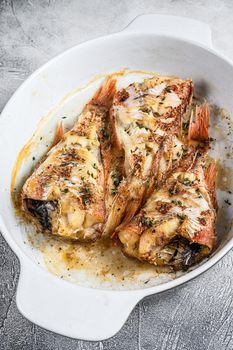 Baked red fish perch in a baking dish. White background. Top view.