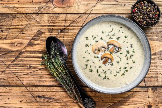 Mushroom cream soup in a plate. Wooden background. Top view. Copy space.