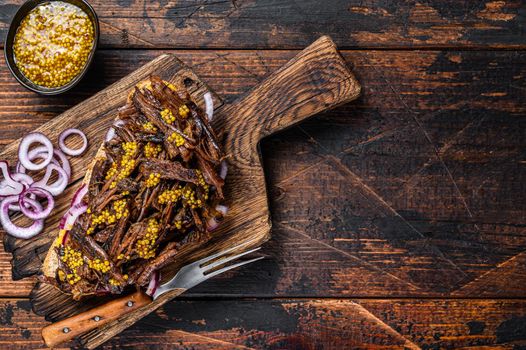 BBQ Sandwich with slow roasted pulled pork meat. Dark wooden background. Top view. Copy space.