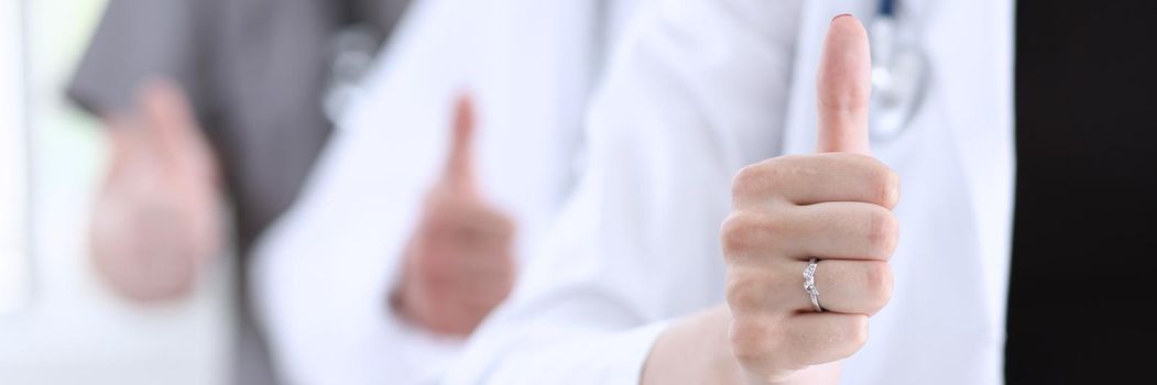 Group of doctor hands show OK or approval sign with thumb up closeup. High level service, best treatment, 911, healthy lifestyle, satisfied patient, therapeutist consultation, physical concept
