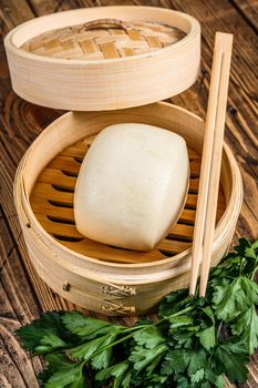 Chinese Steamed Buns in traditional bamboo steamer. Wooden background. Top view.
