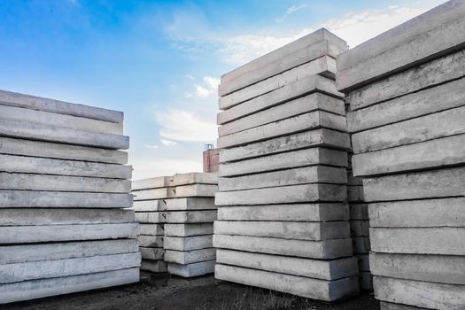Concrete blocks at a construction site. Concrete structures in an industrial area against a blue sky with clouds.