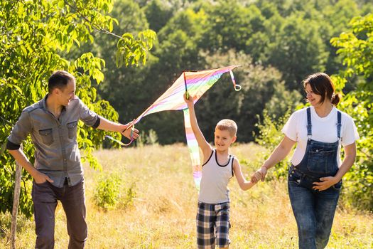 Young parents go with the son on the wheat field . The little son is happy when he is played.