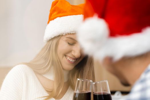 Young couple in Santa hats drinking wine and celebrating Christmas, close up