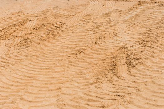 Industrial vehicle tracks on the sand road wheel tire trail at a construction site.