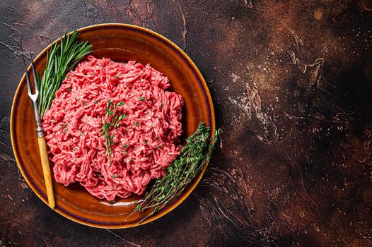 Raw mince beef and lamb meat on a rustic plate with herbs. Dark background. Top view. Copy space.