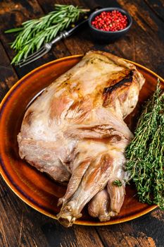 Roasted whole lamb shoulder. Dark wooden background. Top view.