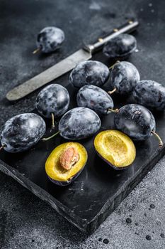 Garden plums on stone table. Black background. Top view.