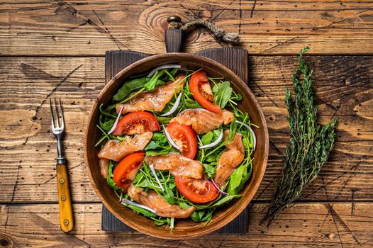 Vegetable salad with smoked salmon, arugula, tomato and green vegetables. wooden background. Top View.