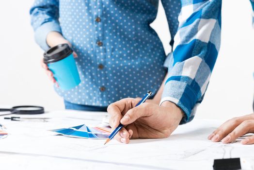 Professional designers discussing architecture project. Creative teamwork and project brainstorming. Close up human hands and construction drawing of building on desk. Industrial engineering company.