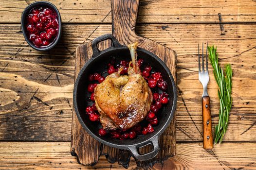 Fried duck leg with cranberrie sauce in a pan. wooden background. top view.