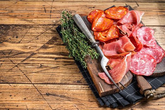 Cured meat platter served as traditional Spanish tapas. salami, jamon, choriso sausages on a wooden board. wooden background. Top view. Copy space.