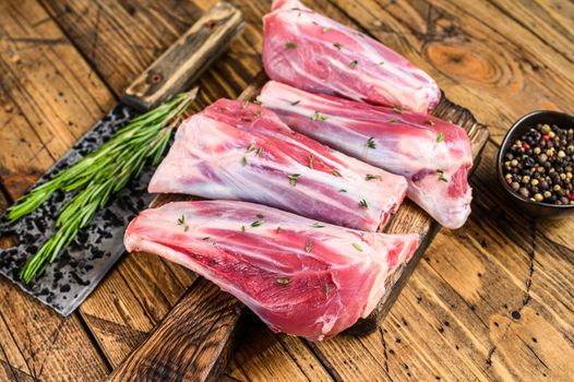 Fresh Raw lamb shanks meat with herbs and pepper. wooden background. Top view.