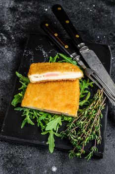 Fried cordon bleu meat chicken cutlet with ham and cheese. Black background. Top view.